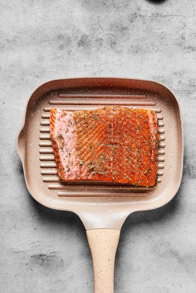 Seasoned raw salmon on a grill pan.