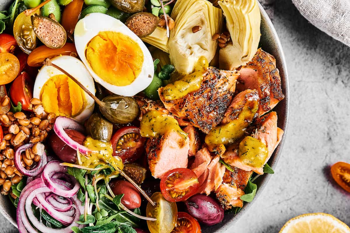 Grilled salmon salad with hard-boiled eggs, pickled red onions, halved tomatoes, and more.