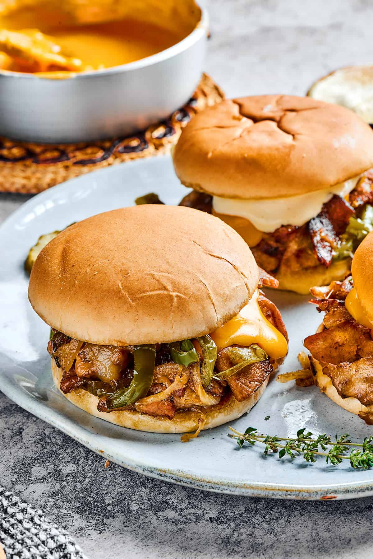 Two steak sandwiches with onions, melted cheese, and bell peppers.