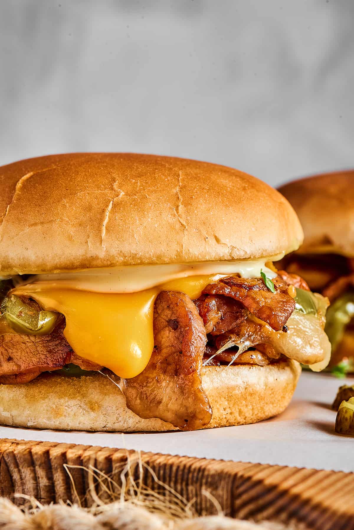 Philly cheesesteak burgers on a parchment-lined cutting board.