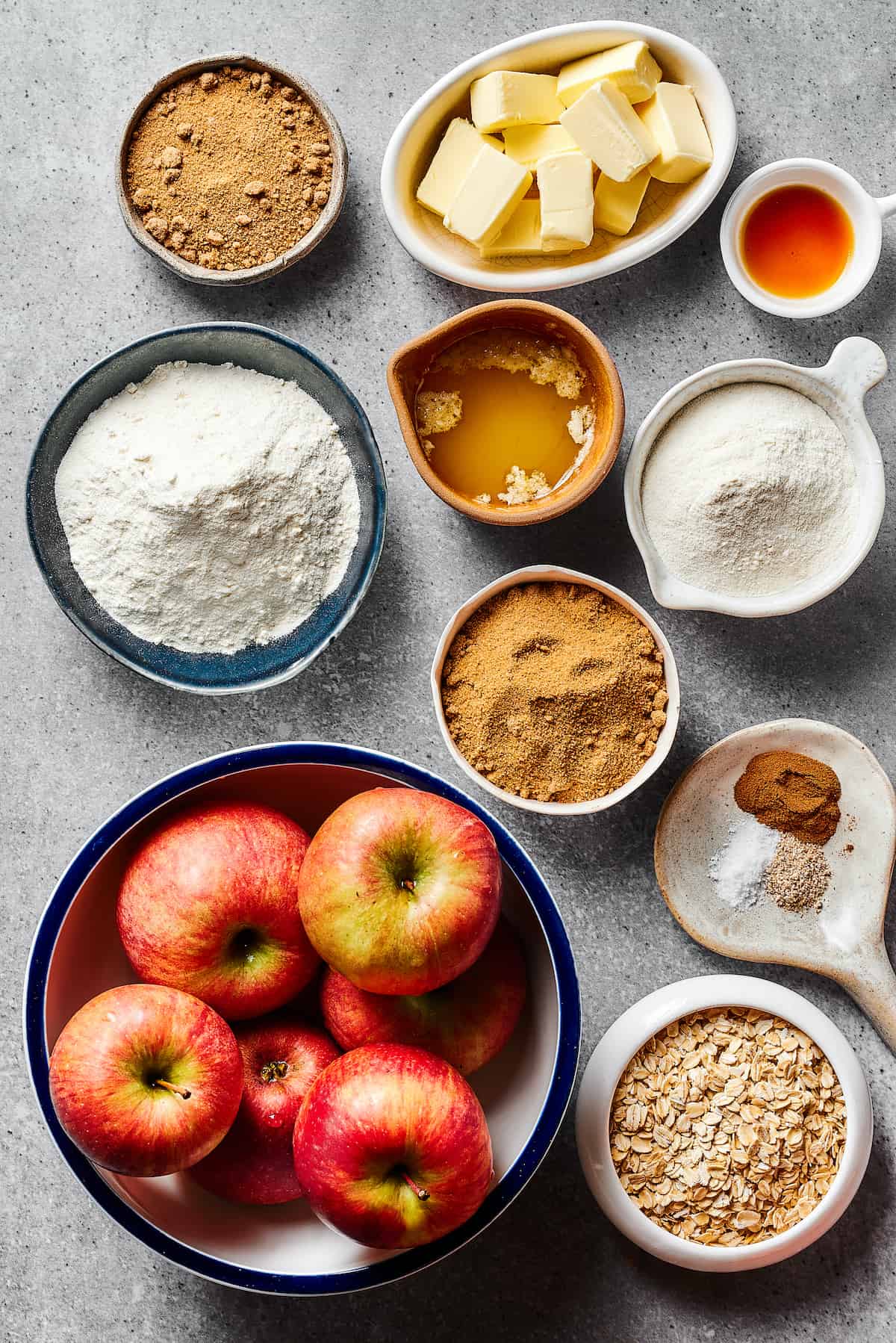 From top left: Brown sugar, butter, vanilla, flour, melted butter, additional flour, additional brown sugar, spices, apples, oats.