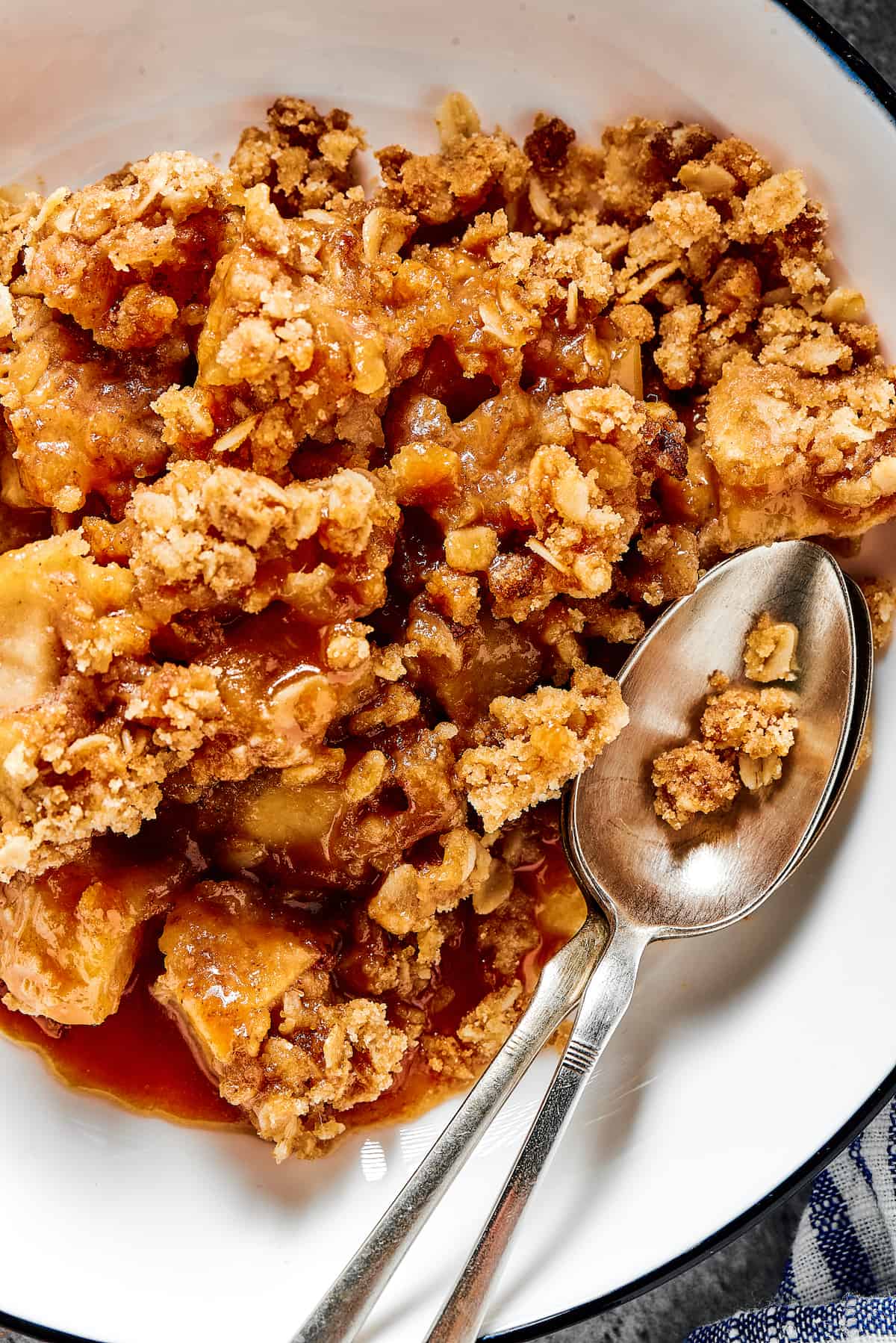 Close-up shot of apple crisp in a dessert bowl, with a spoon.