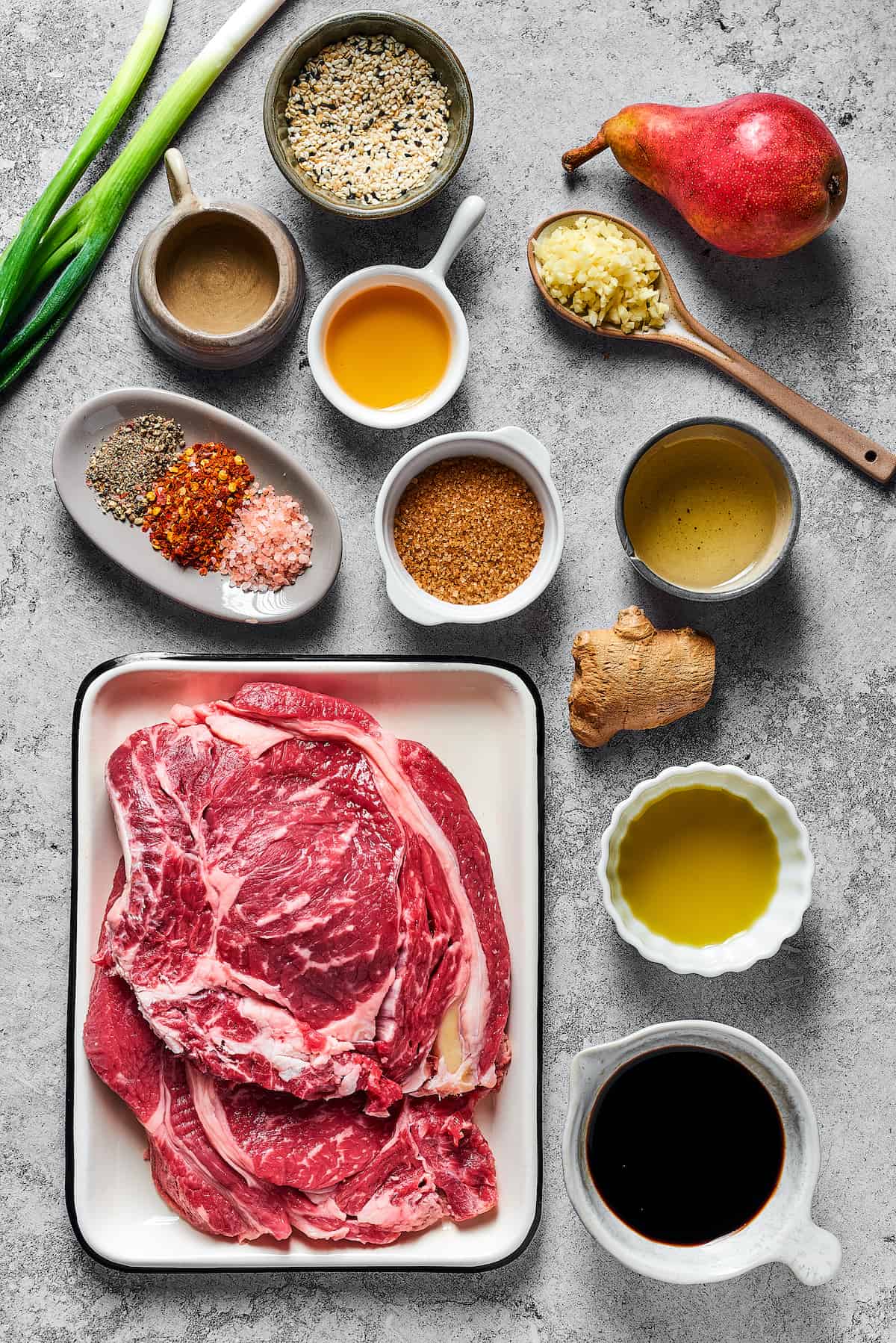 From top left: Green onions, toasted sesame seeds, a fresh pear, sesame oil, mirin, minced garlic, spices, brown sugar, oil, steak, ginger, soy sauce.