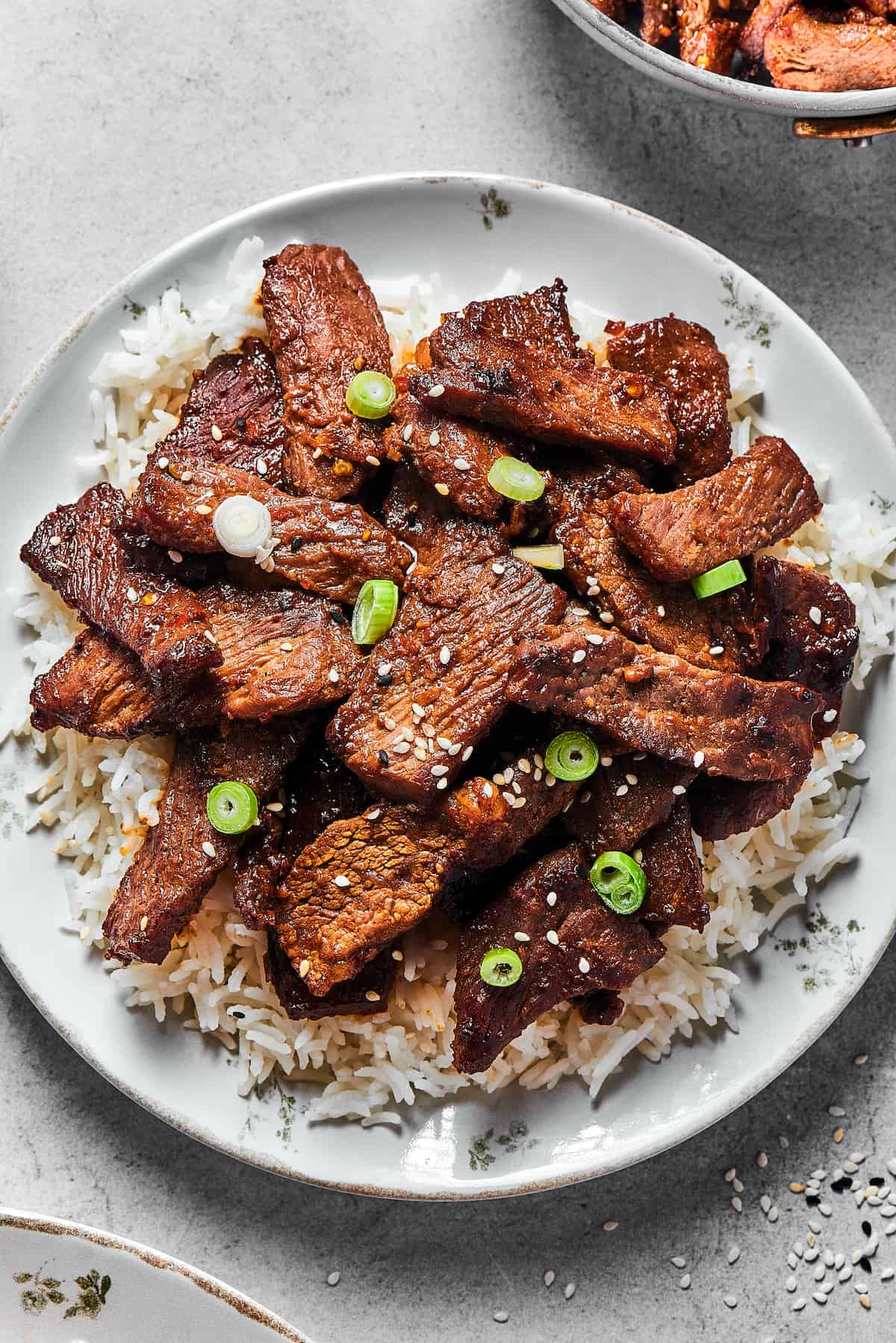 Beef bulgogi served onto a white plate, over a bed of rice.