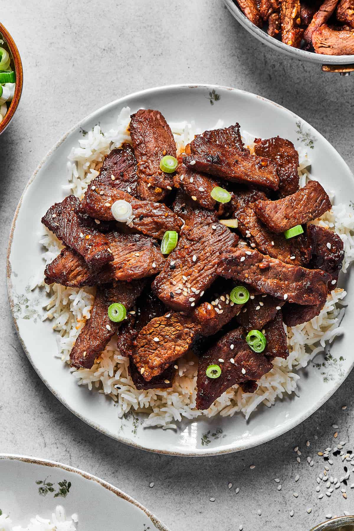 A plate of bulgogi with other dishes visible at the edges of the shot.