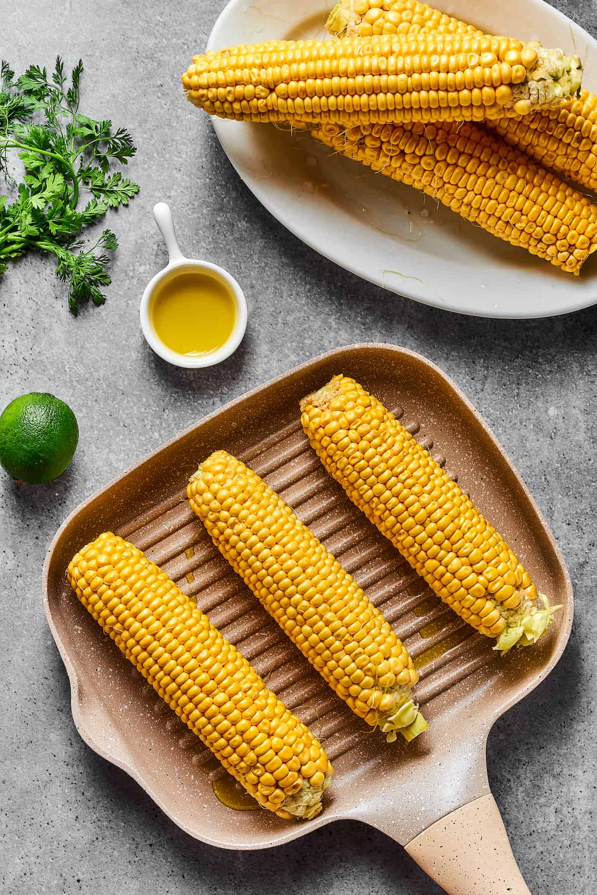 Ears of corn cooking on a grill pan.