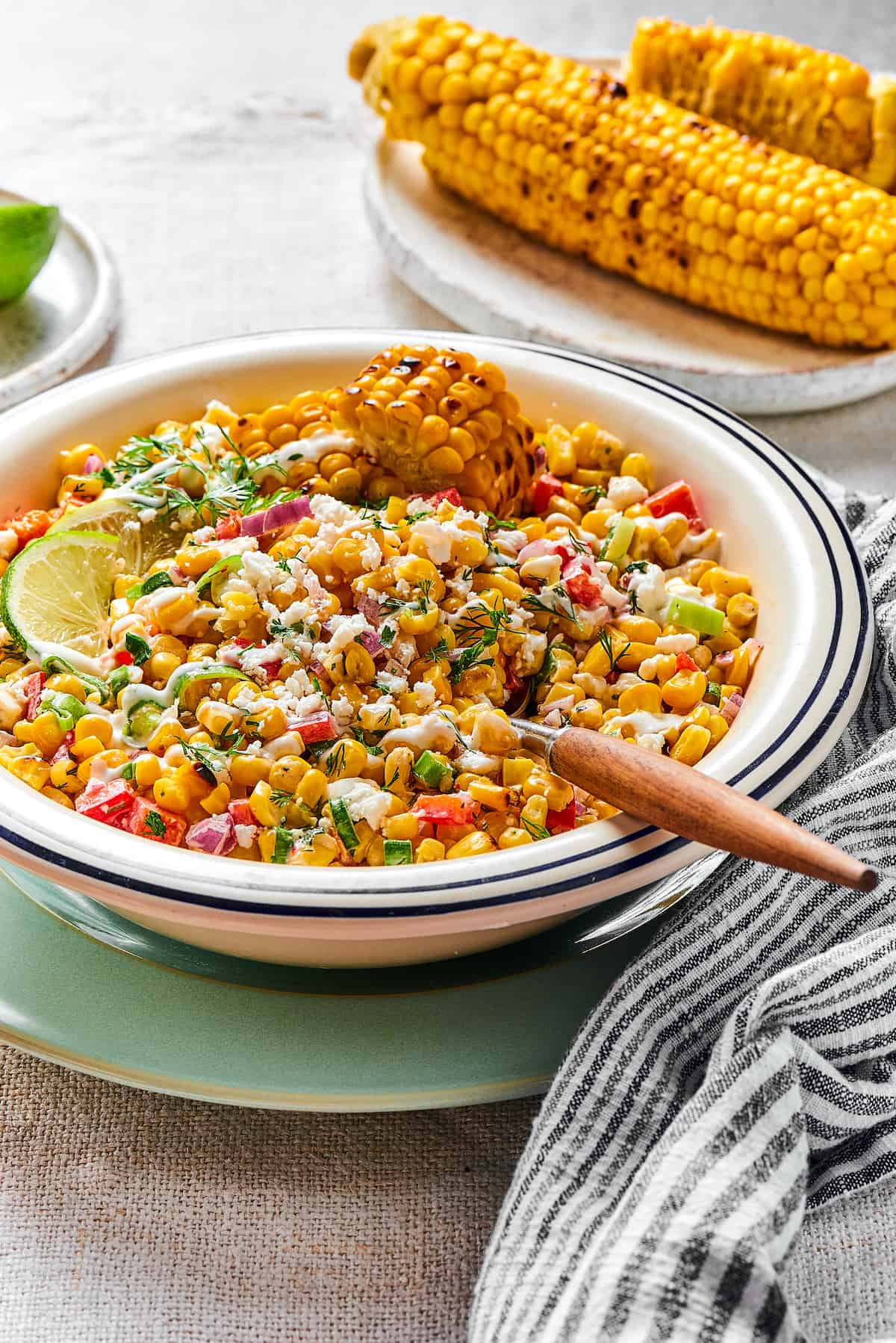 Elote salad in a bowl with a wooden-handled spoon.