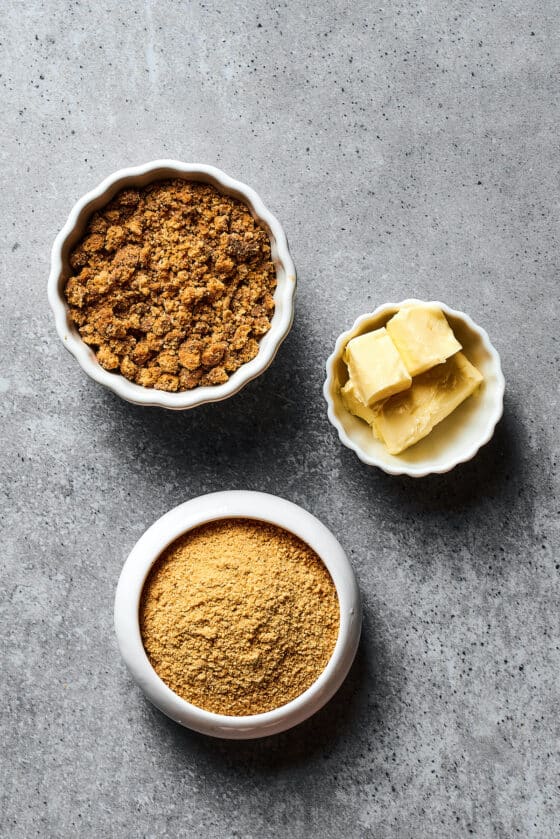 From top: Graham cracker crumbs, butter, and brown sugar in separate dishes.