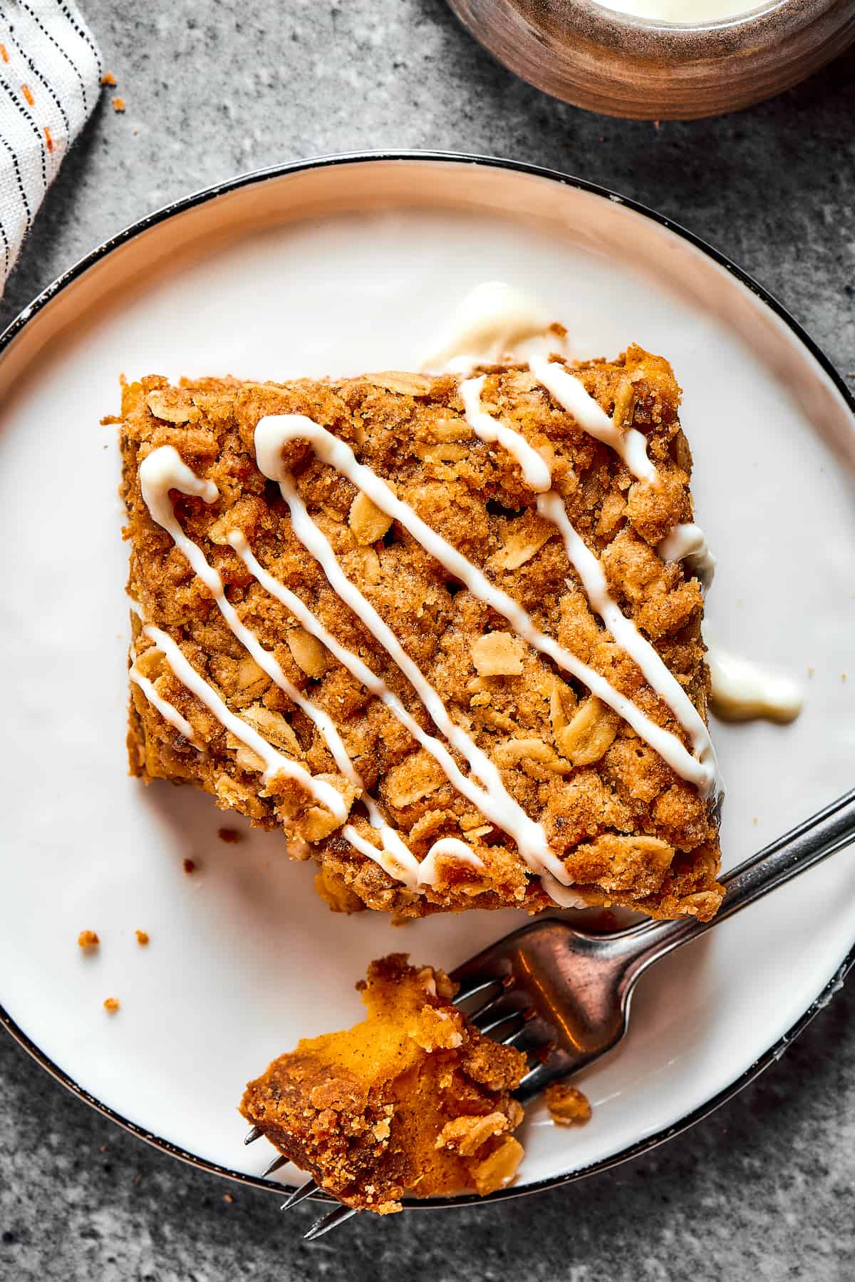 A pumpkin cheesecake square on a plate, with one bite broken off and resting on a fork.