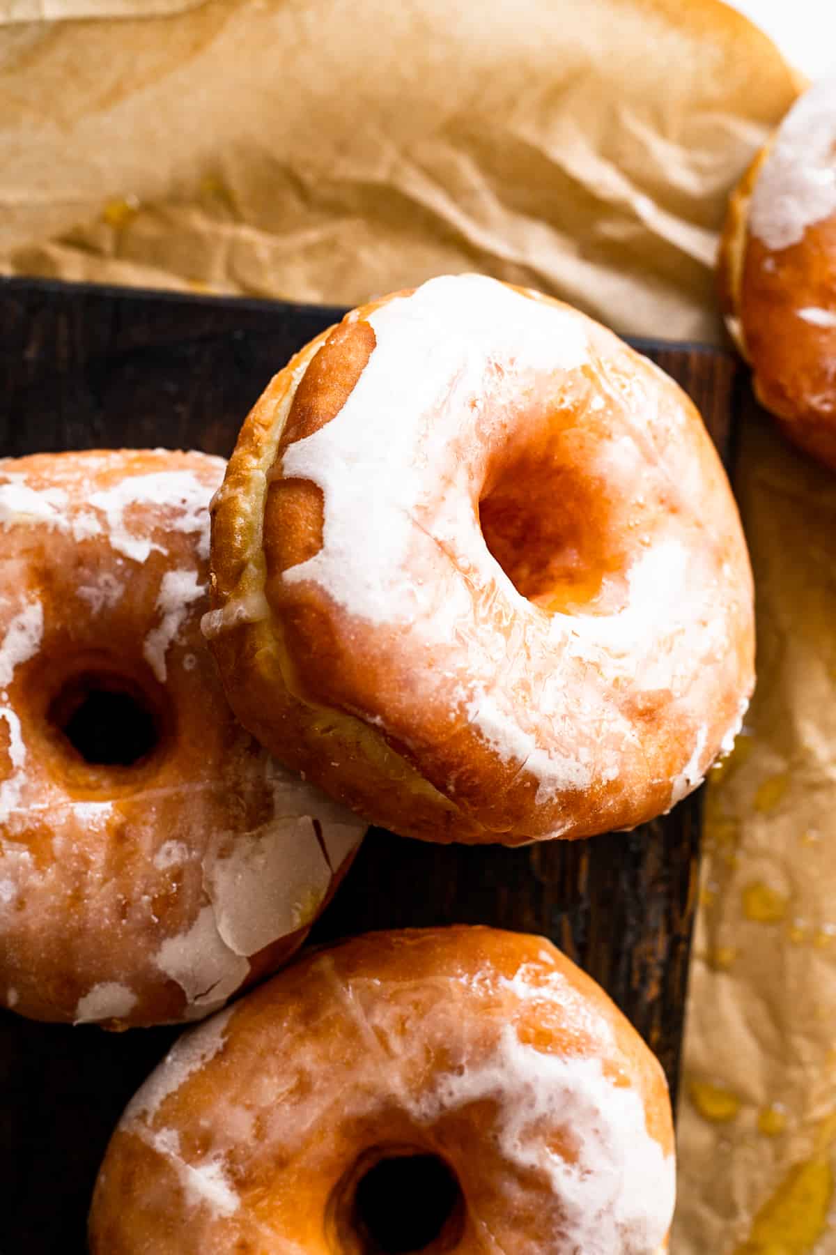 apple cider maple glazed doughnuts resting on a wooden board.