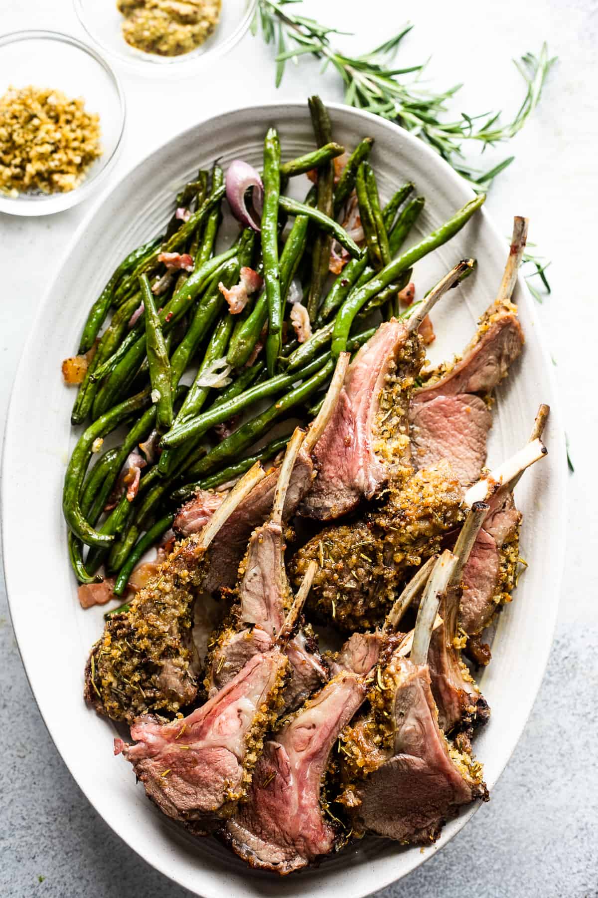 overhead shot of lamb chops arranged on a serving platter with a side of green beans placed above the chops.