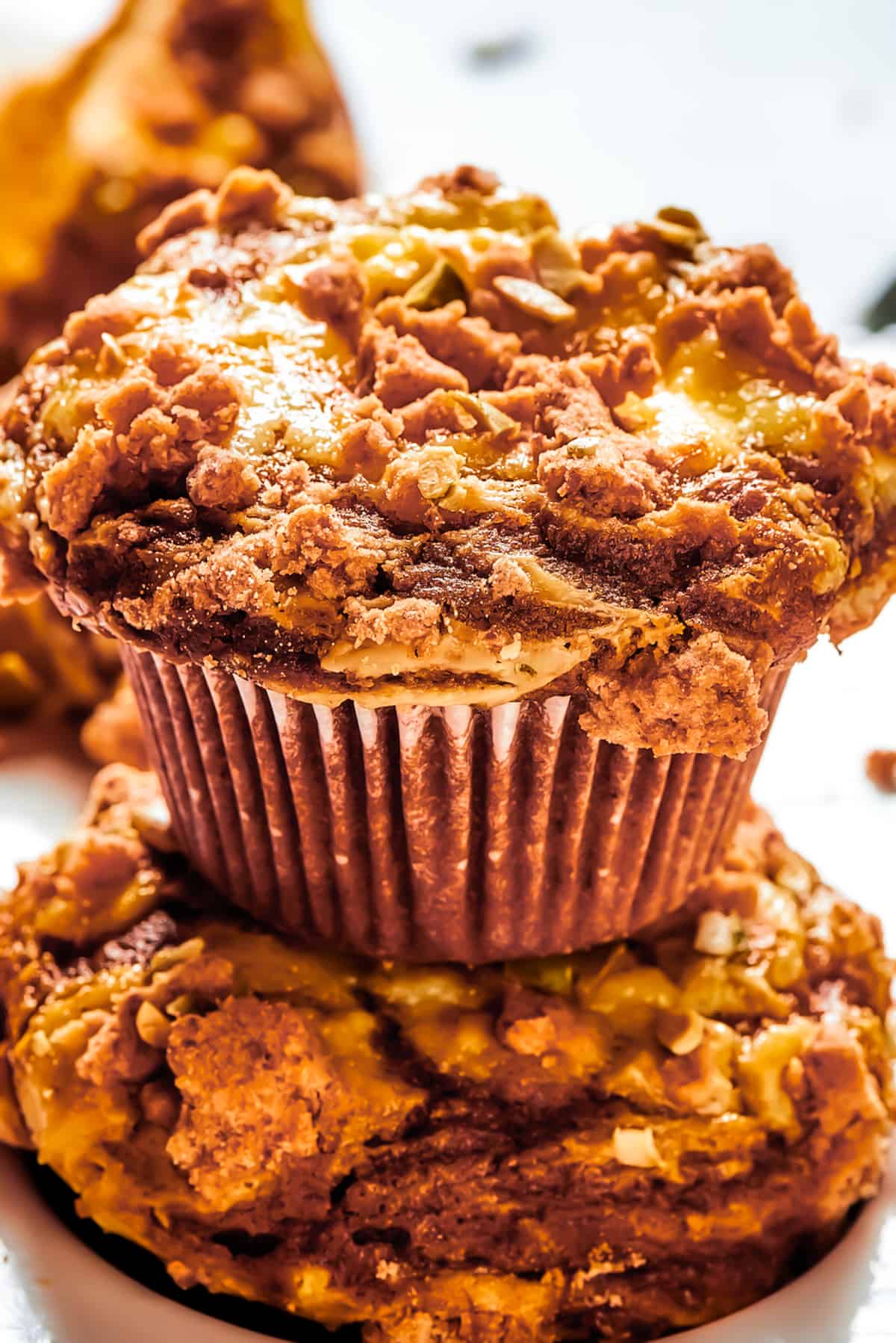 A pumpkin cream cheese muffin set atop of another muffin, and arranged on a work surface.