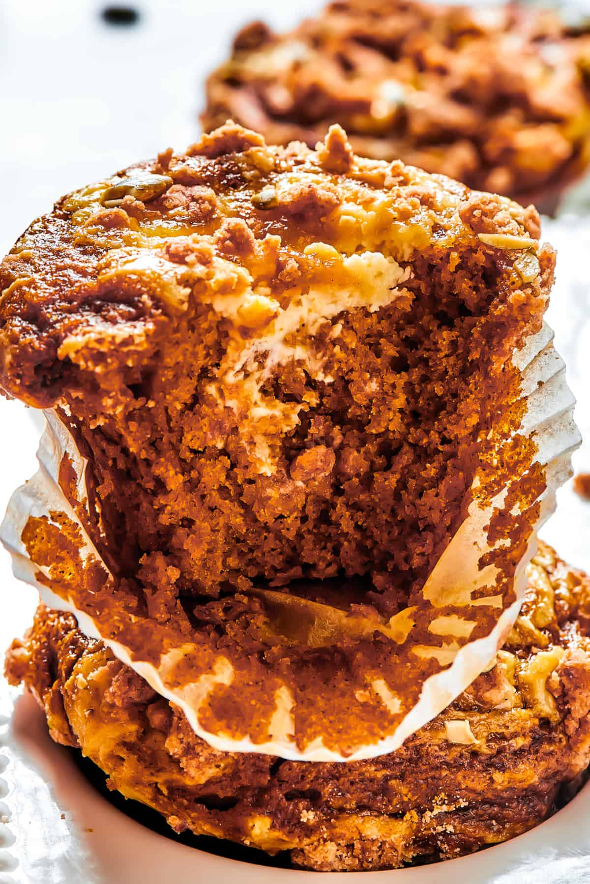 A pumpkin muffin broken in half with the paper muffin cup peeled away.