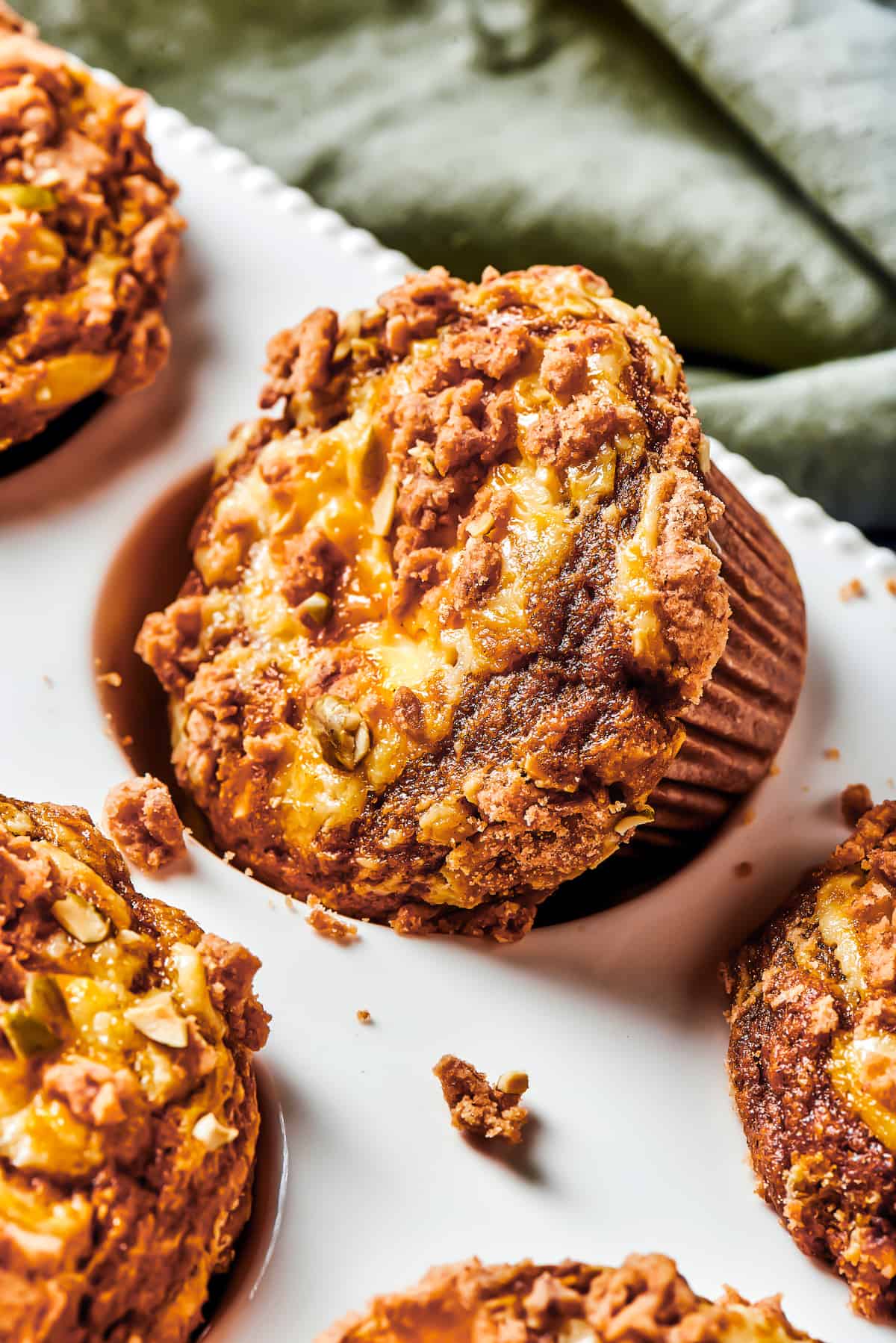 A muffin tin with one muffin turned diagonally in its well. Small pieces of topping have fallen off onto the muffin tin.