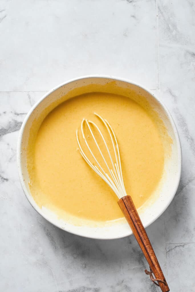 Cornbread batter in a mixing bowl with a whisk.
