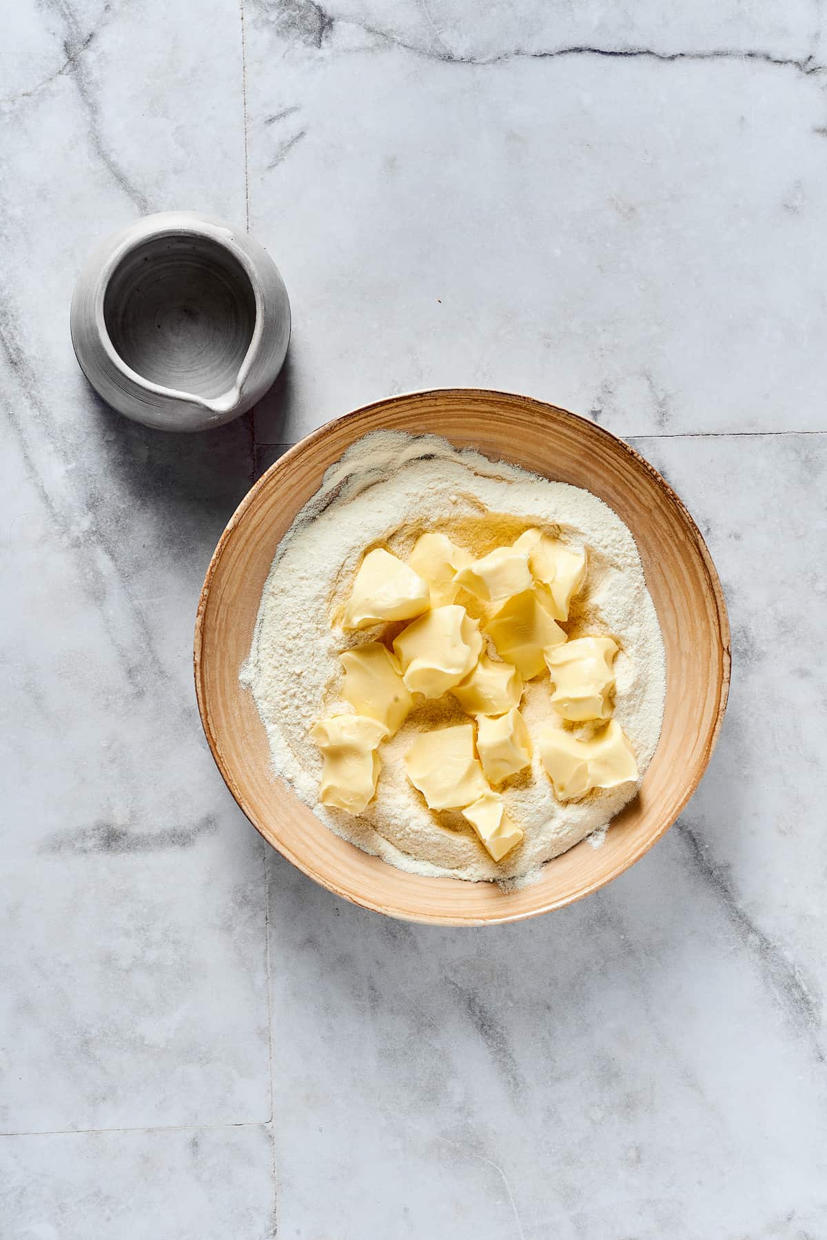 Butter being added to dry baking ingredients.