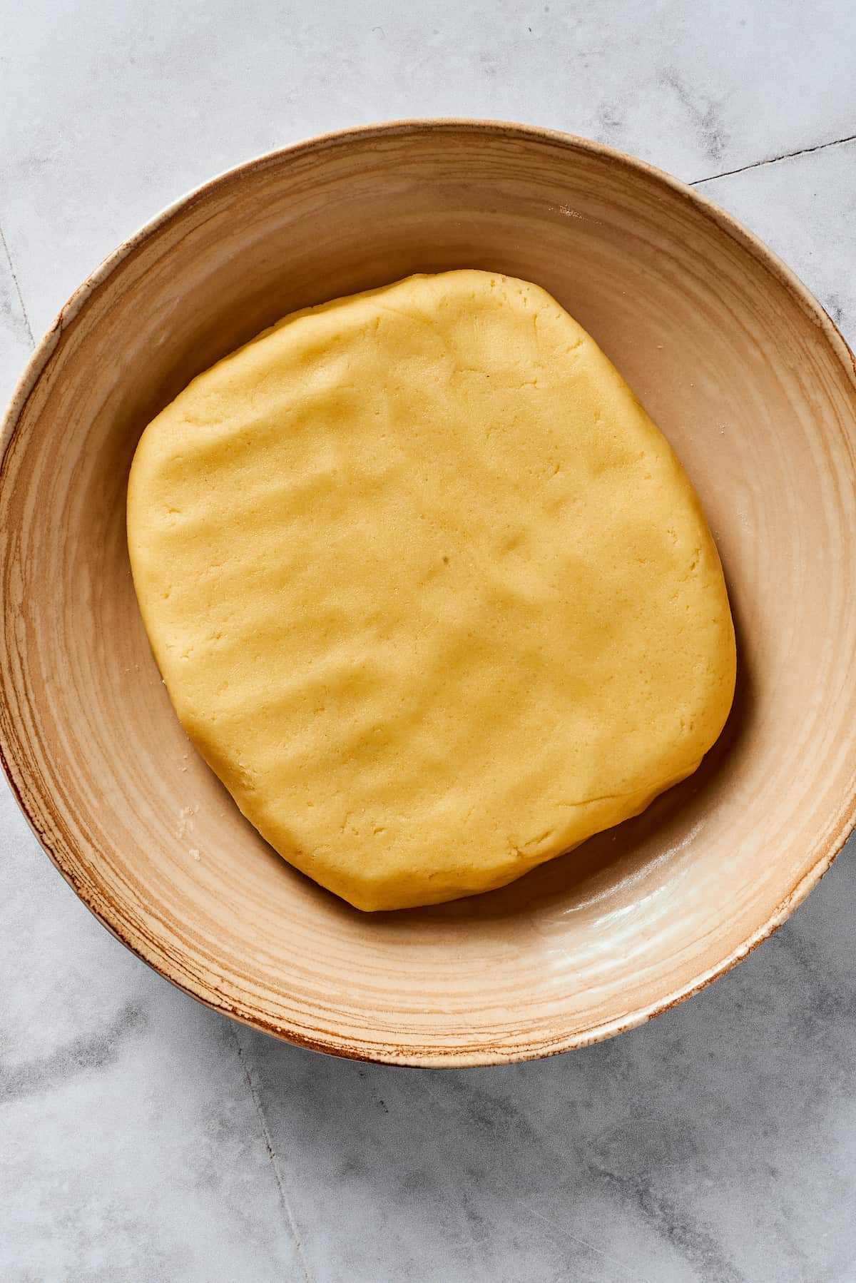 A flattened piece of pie dough in a mixing bowl.