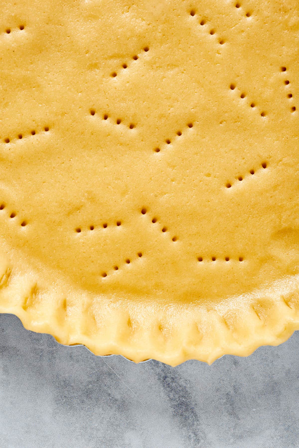 Unbaked pie dough shaped into a pie plate and pricked with a fork.