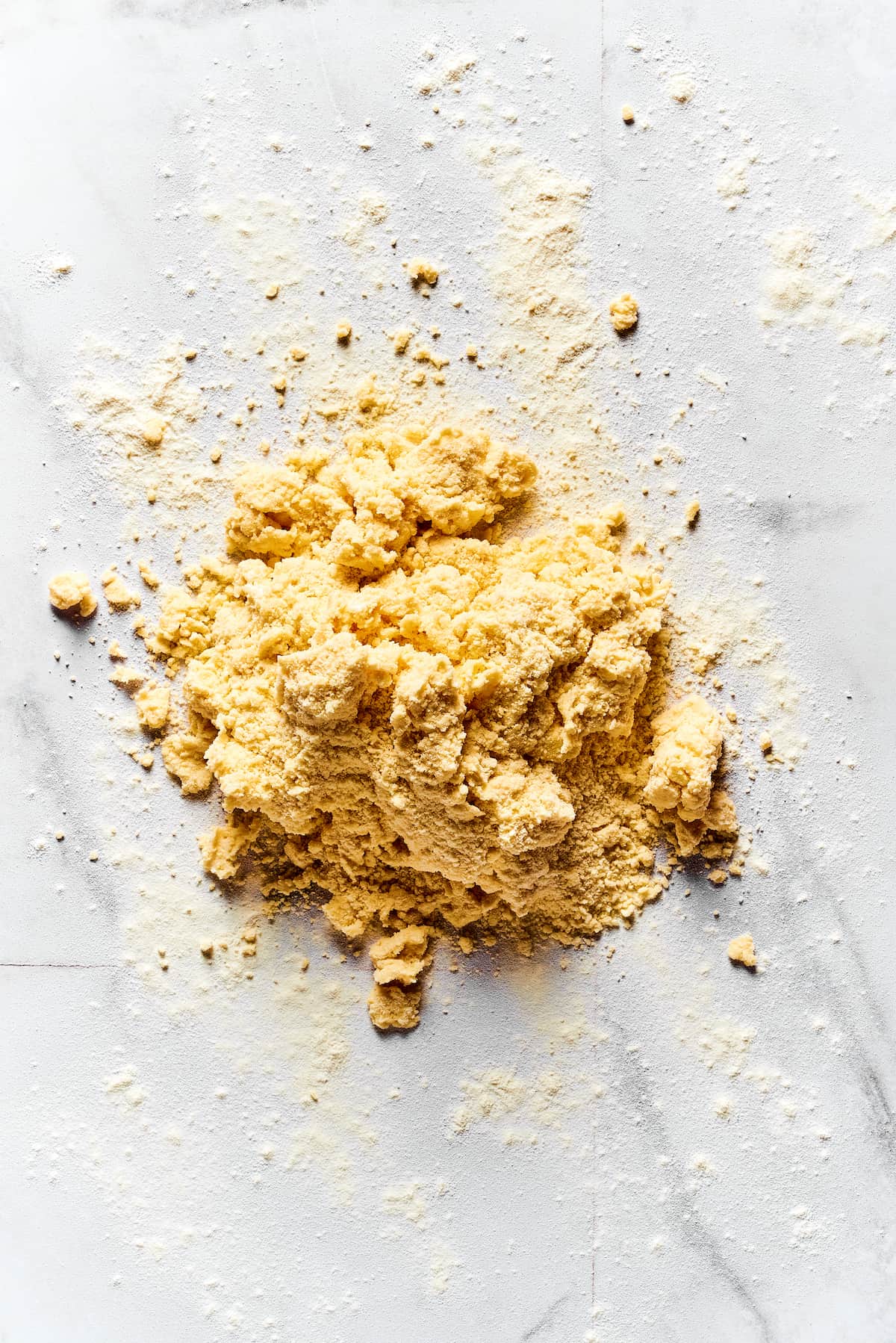 Crumbly biscuit dough on a marble work surface.