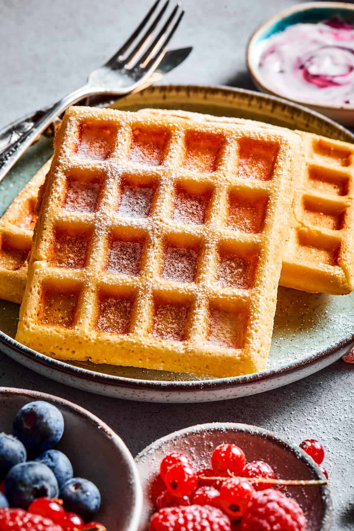 Golden brown waffles dusted with powdered sugar.