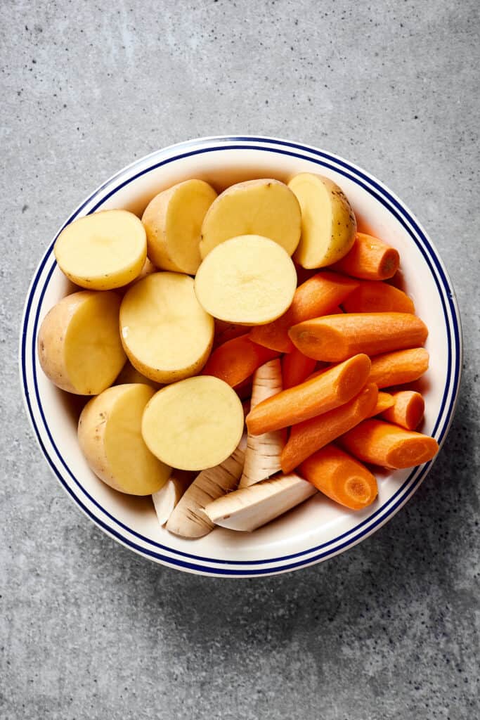A bowl of cut-up potatoes, carrots, and parsnips.