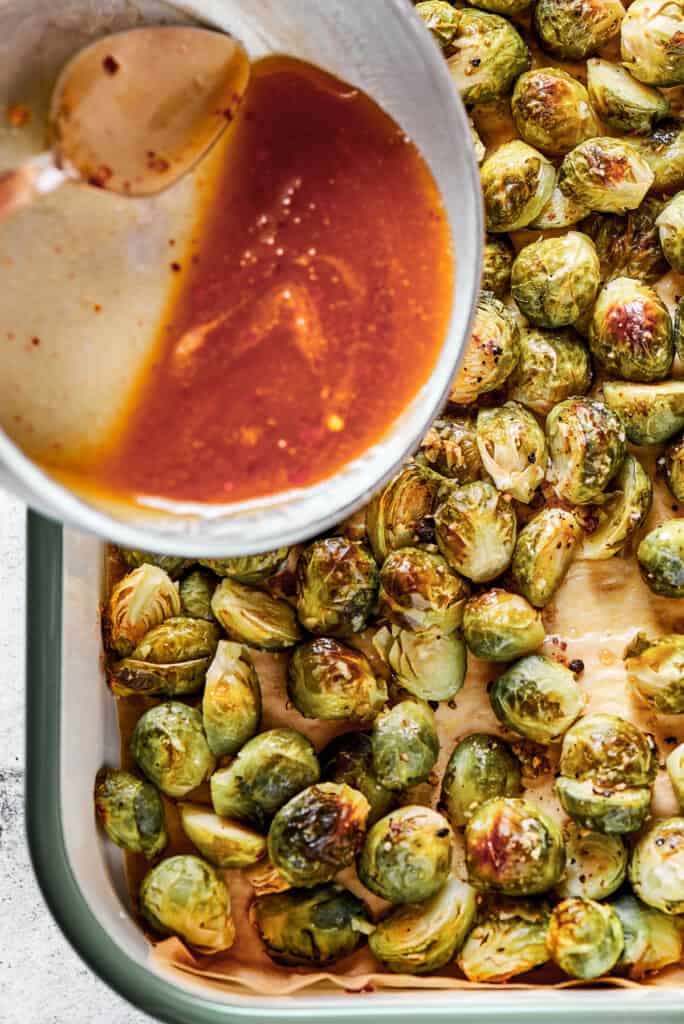 Adding glaze to roasted brussel sprouts.