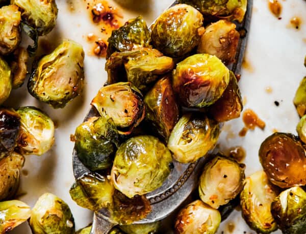 A tray of roasted brussel sprouts with a silver serving spoon.