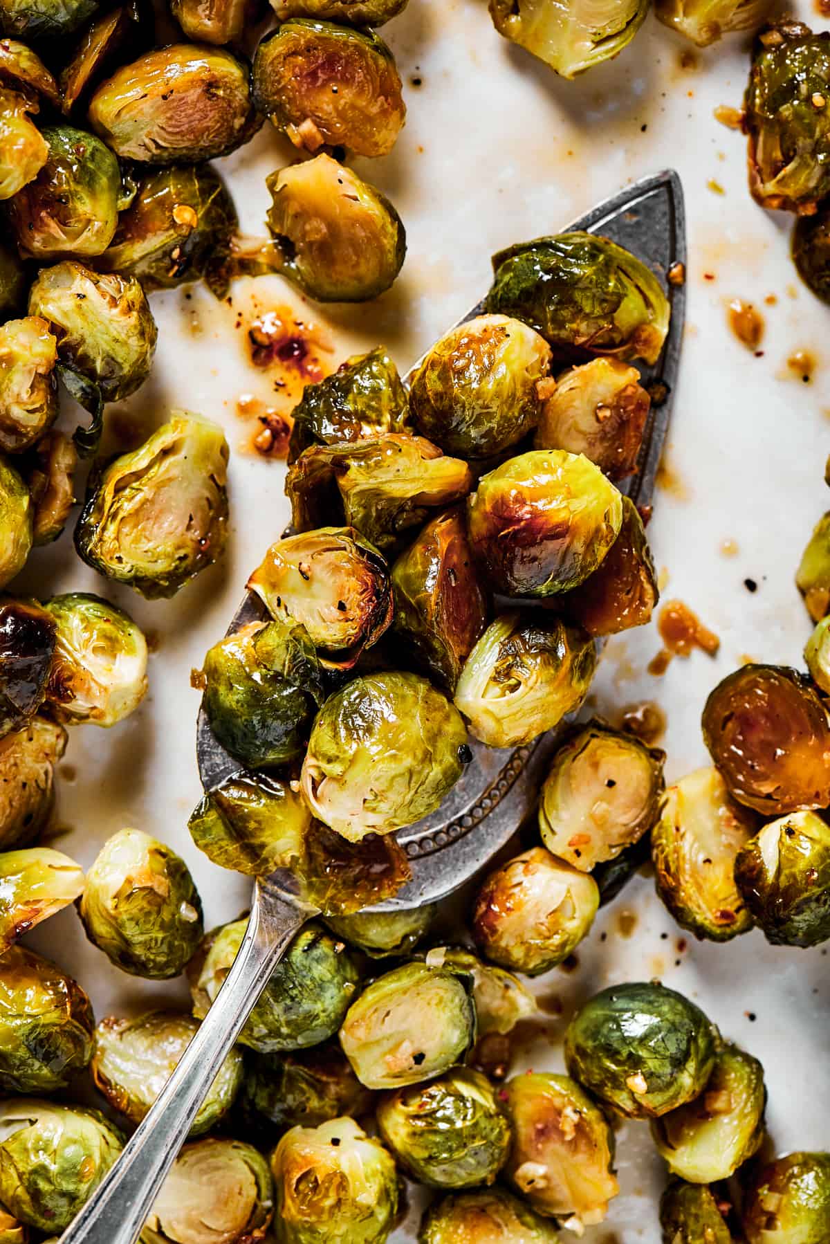 A tray of roasted brussel sprouts with a silver serving spoon.