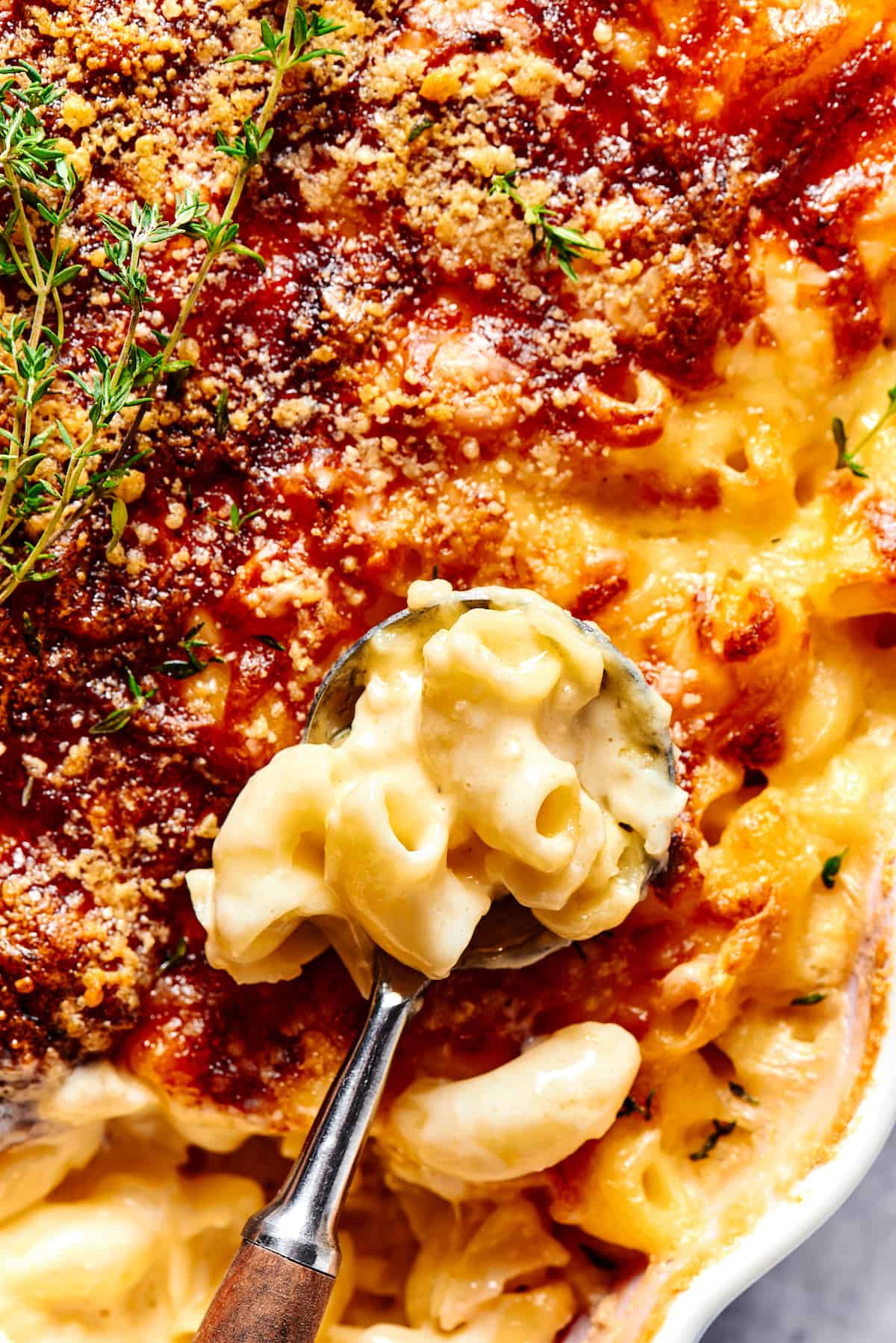 Spooning baked macaroni out of a casserole dish.