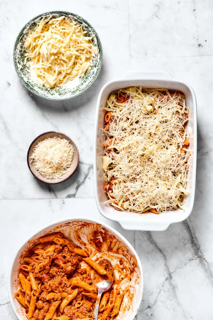 Cheese sprinkled over pasta in a baking dish.