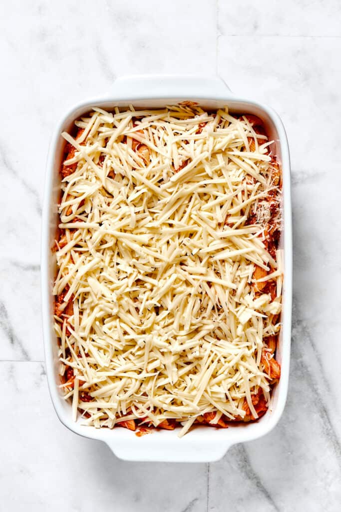 A baking dish filled with layers of pasta in sauce, mozzarella, and parmesan cheese.