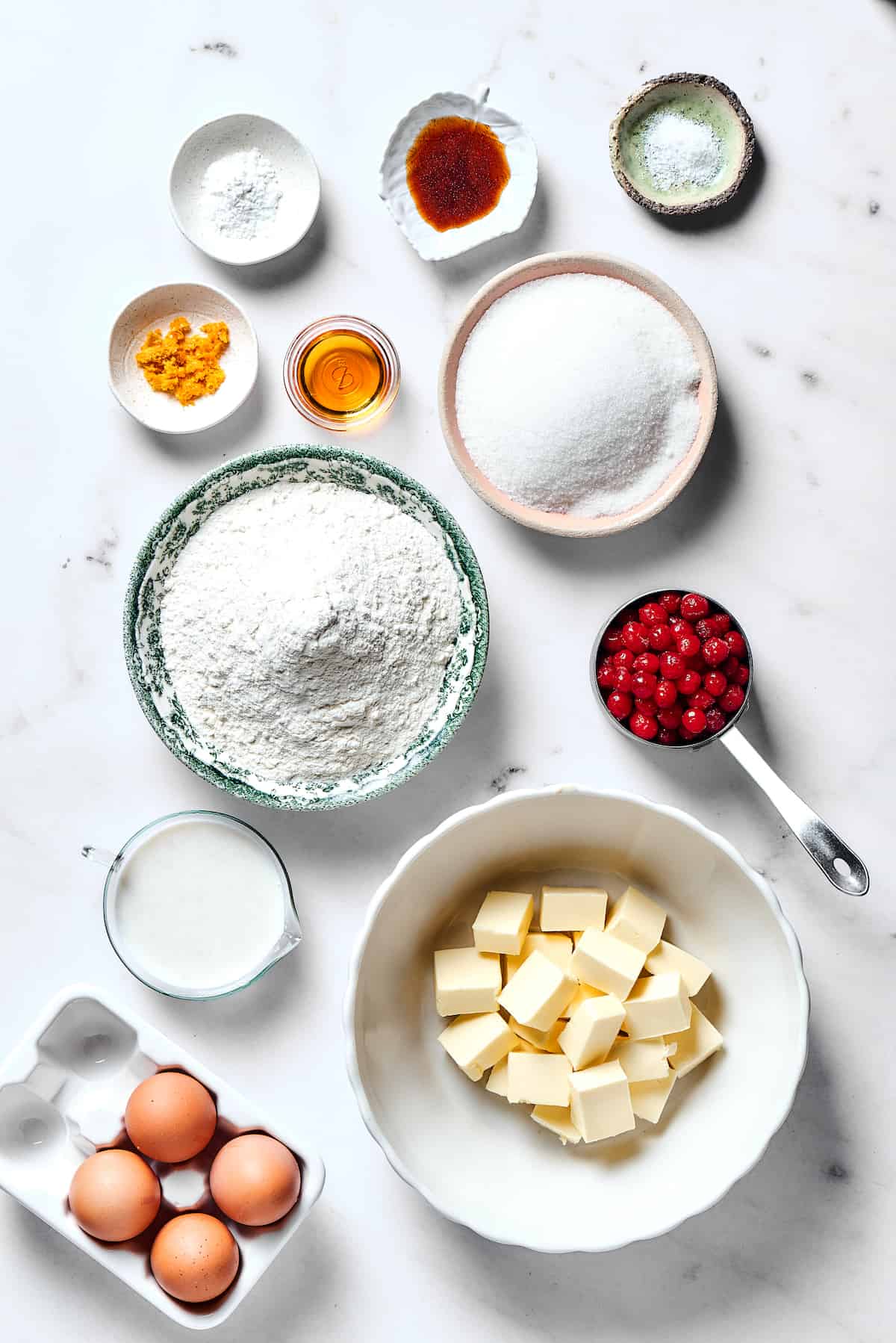 From top left: Baking powder, vanilla, salt, orange zest, orange liqueur, sugar, flour, cranberries, buttermilk, butter, eggs.