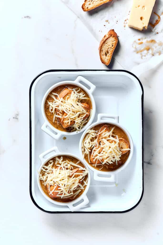 Individual bowls of soup topped with toasted baguette and shredded cheese.