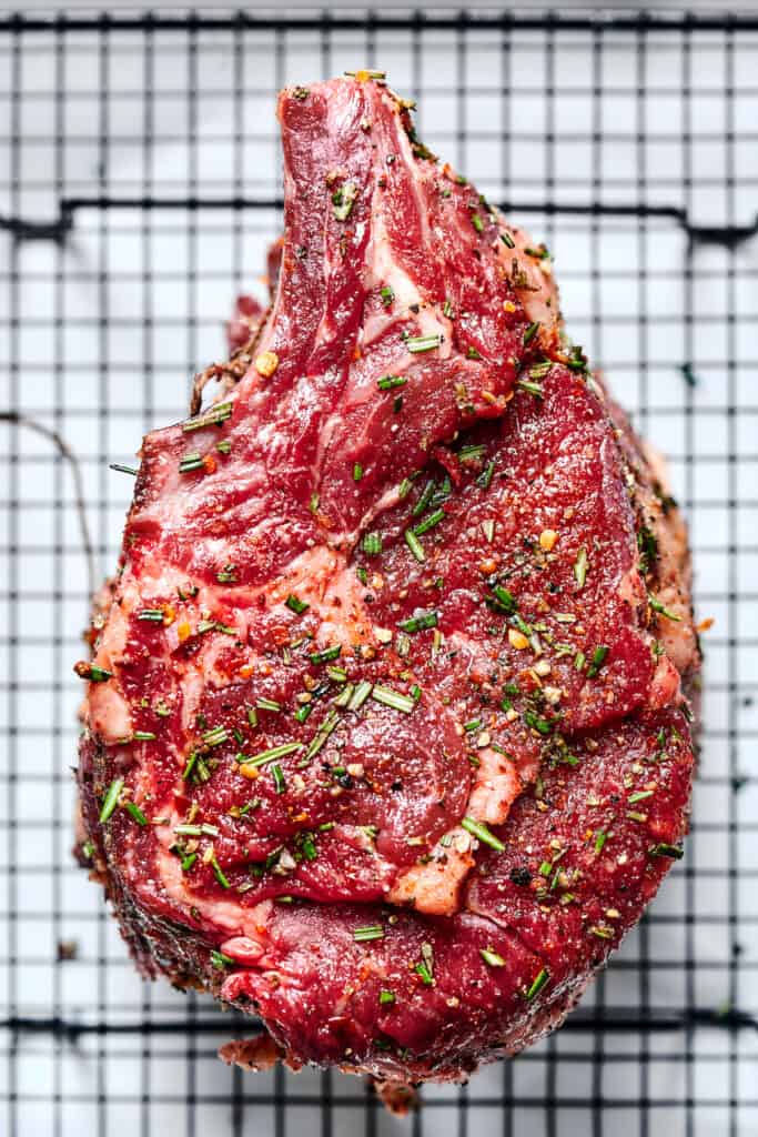 A rib roast sprinkled with sesaonings on a wire rack.