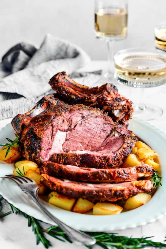 A bone-in rib roast, cooked and plated on a white serving dish.