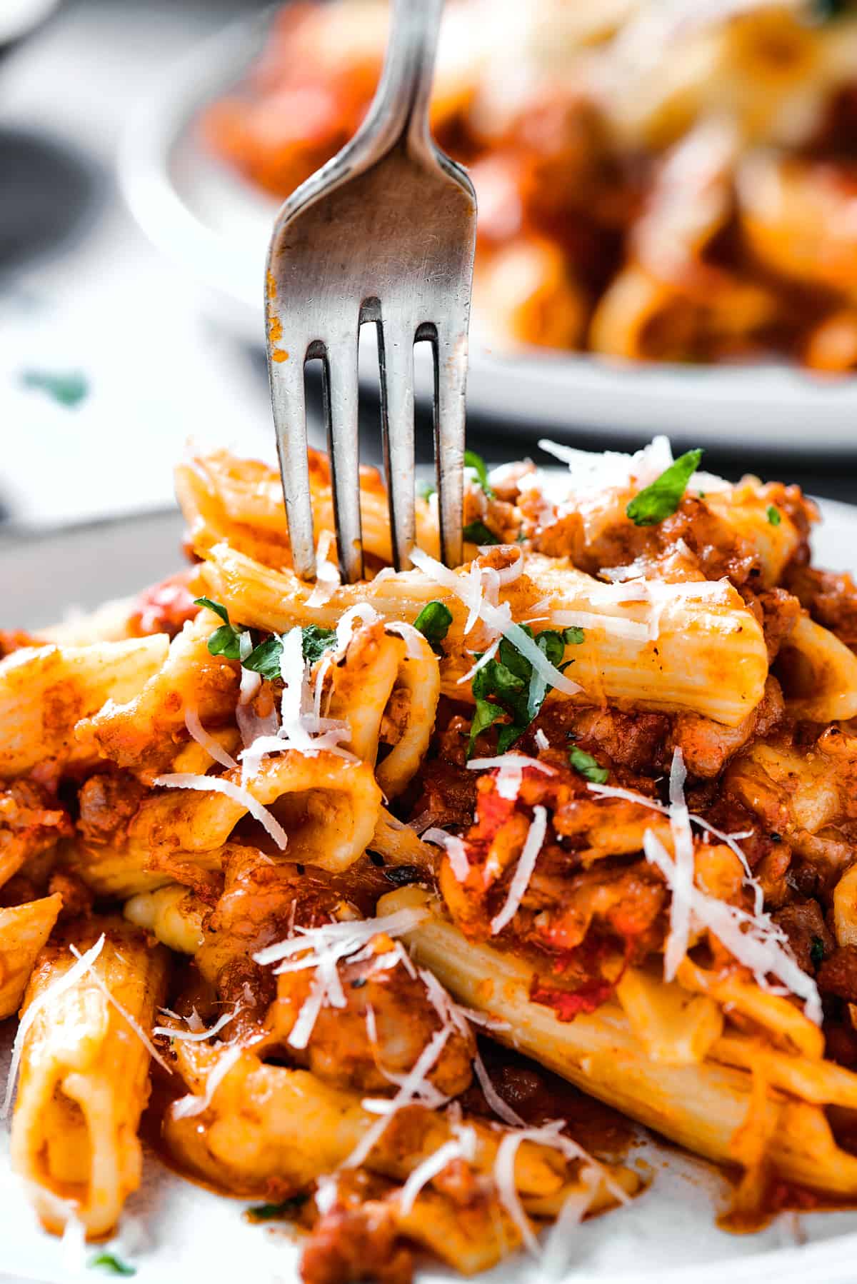A fork digging into a plate of baked mostaccioli.