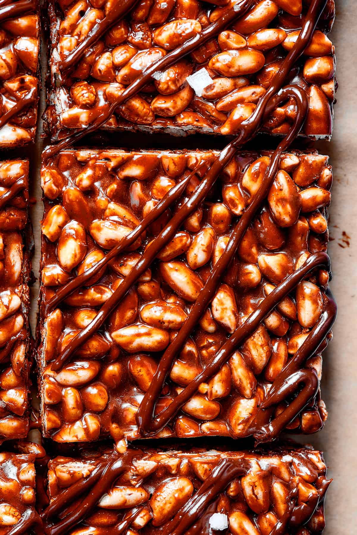 Squares of chocolate rice crispy bars with chocolate drizzled over the top.