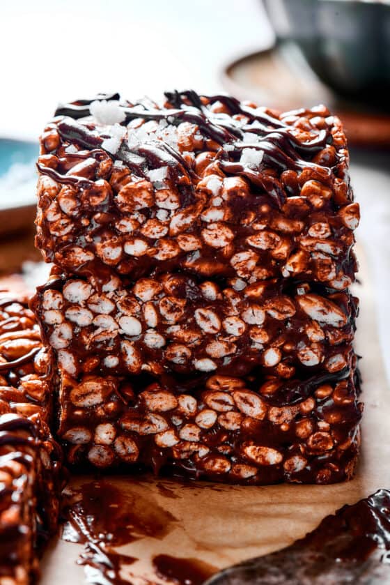 Stacked squares of chocolate rice krispie treats with chocolate topping.