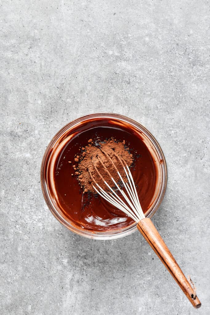 Whisking cocoa powder into a bowl of brownie batter.