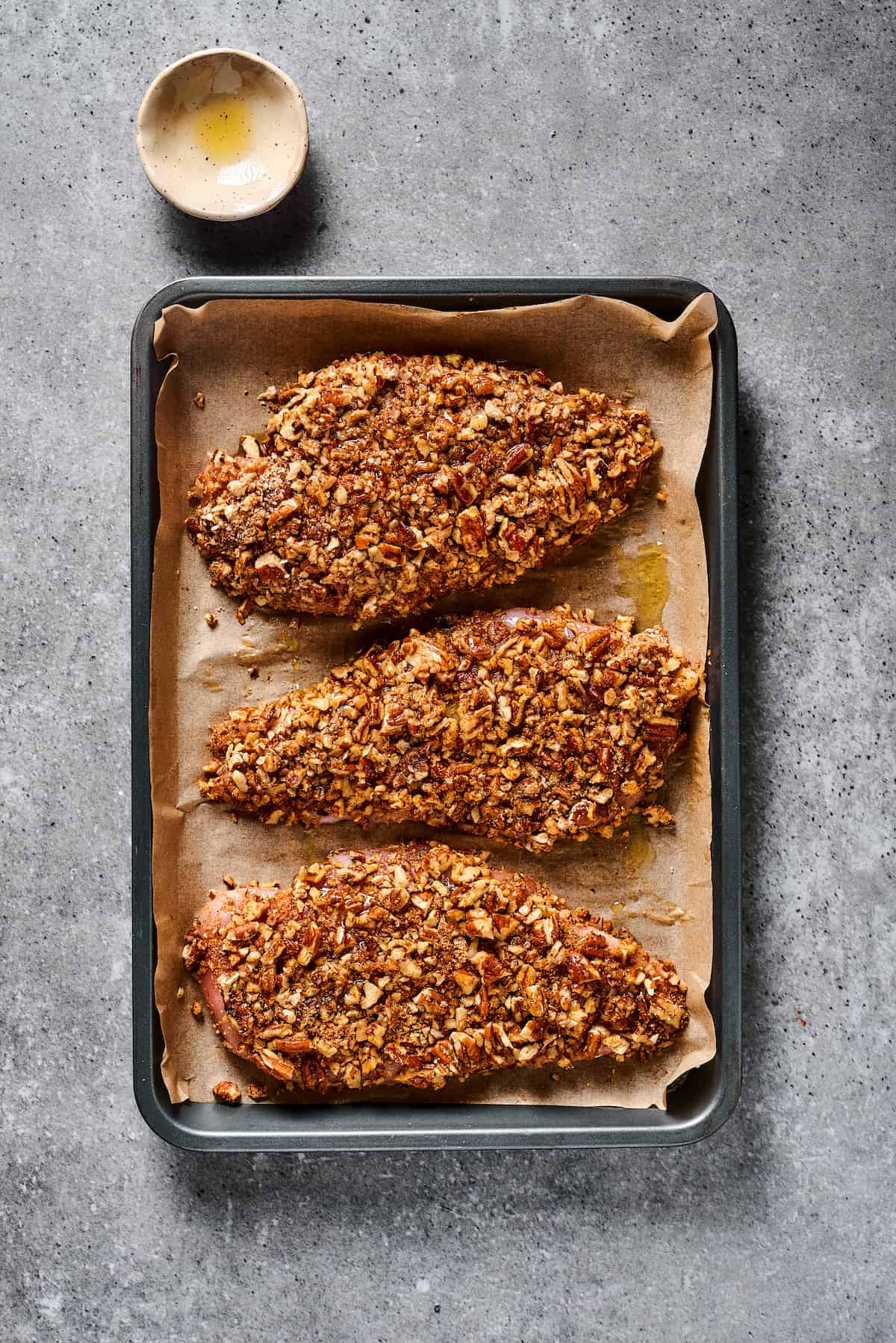 Pecan-coated chicken on a baking sheet.