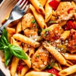 overhead close up of chicken and penne with tomatoes, peppers, and onions.