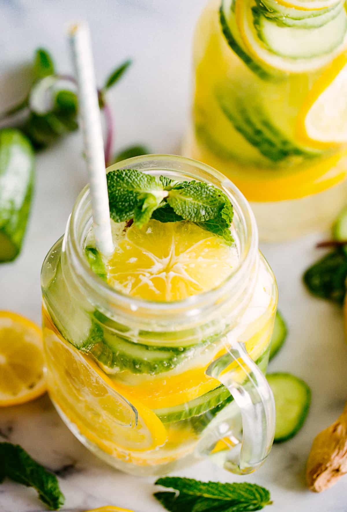 lemon cucumber water in a mason jar glass, served with a straw.