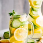 lemon cucumber water served in a mason jar with handle, and in a tall carafe