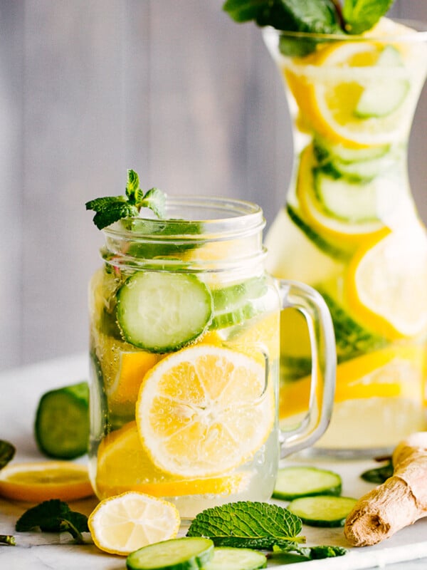 lemon cucumber water served in a mason jar with handle, and in a tall carafe