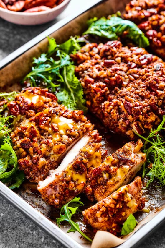 pecan crusted chicken breasts in a stainless steel dish.