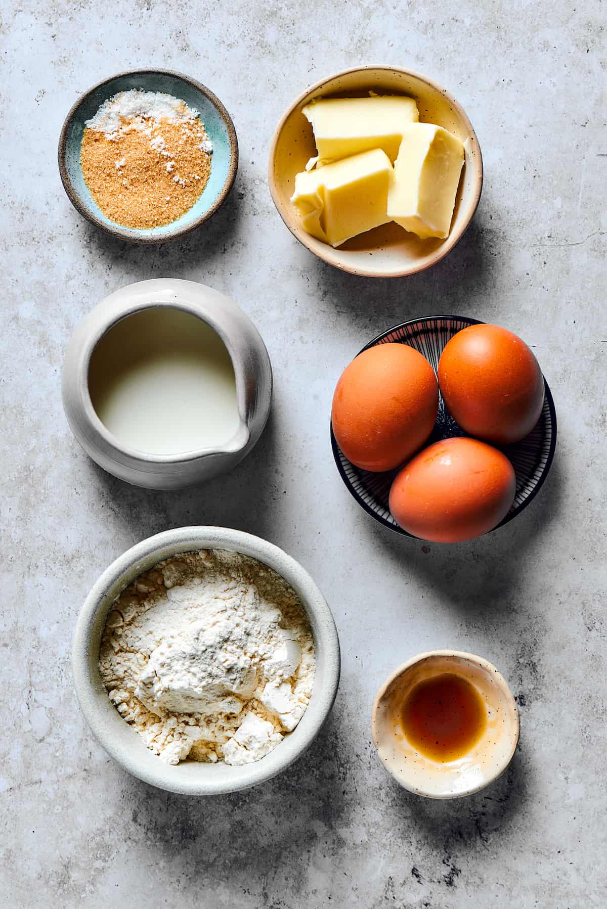 Ingredients for a Dutch baby pancake measured into small dishes and arranged on a work surface.