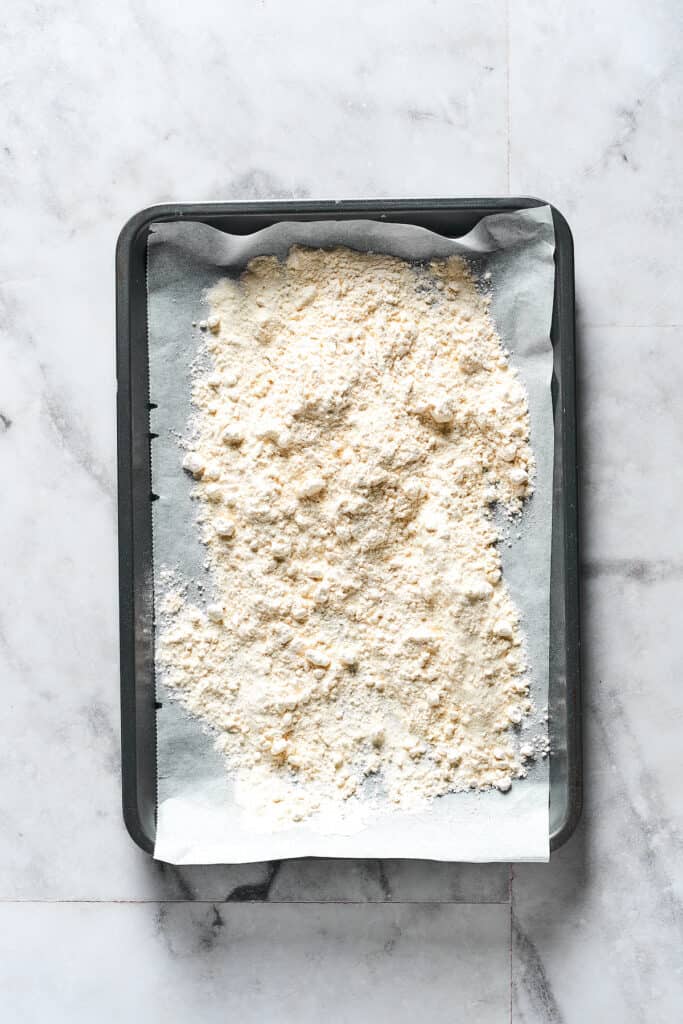 Flour spread out on a parchment-lined baking sheet.