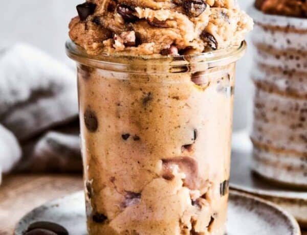 Edible cookie dough in a glass jar placed on a white plate.