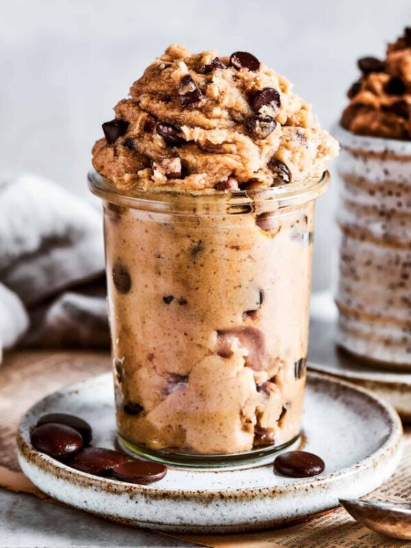 Edible cookie dough in a glass jar placed on a white plate.