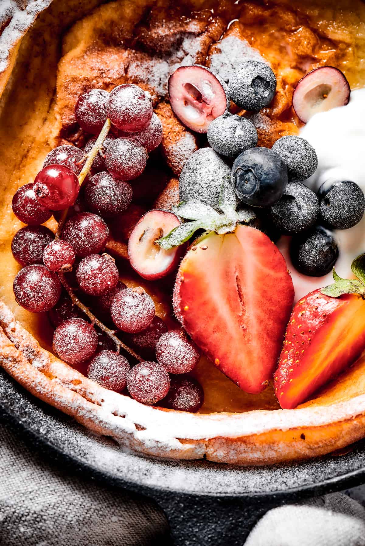 A German pancake topped with powdered sugar and fresh fruit.